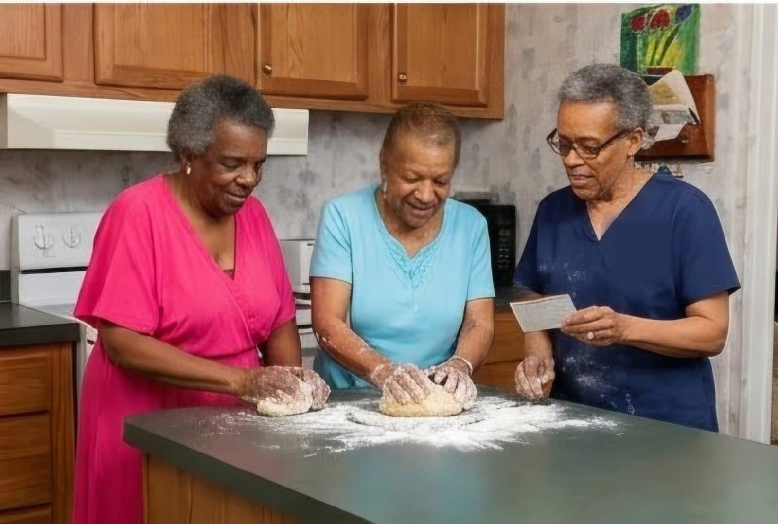A caregiver baking with two clients in their kitchen