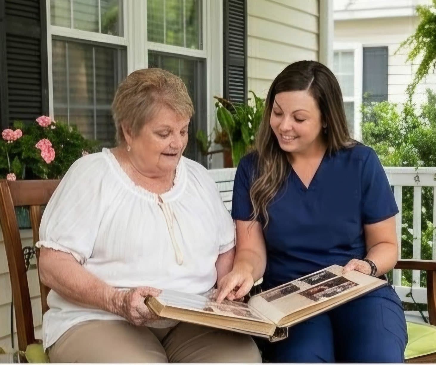 A caregiver and client looking through a photo album on the front porch